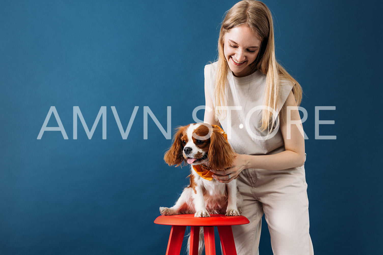 Pet owner standing in the studio. Little dog sitting on a red ch