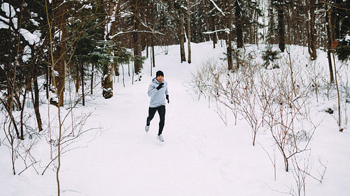 Sportsman running in forest. Young man exercising at winter.