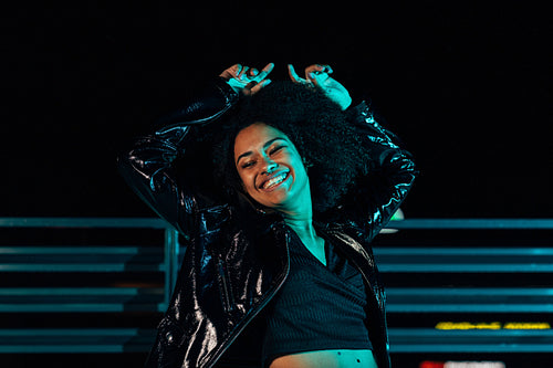 Young happy woman having fun on a roof at night. Smiling female posing outdoors with closed eyes.