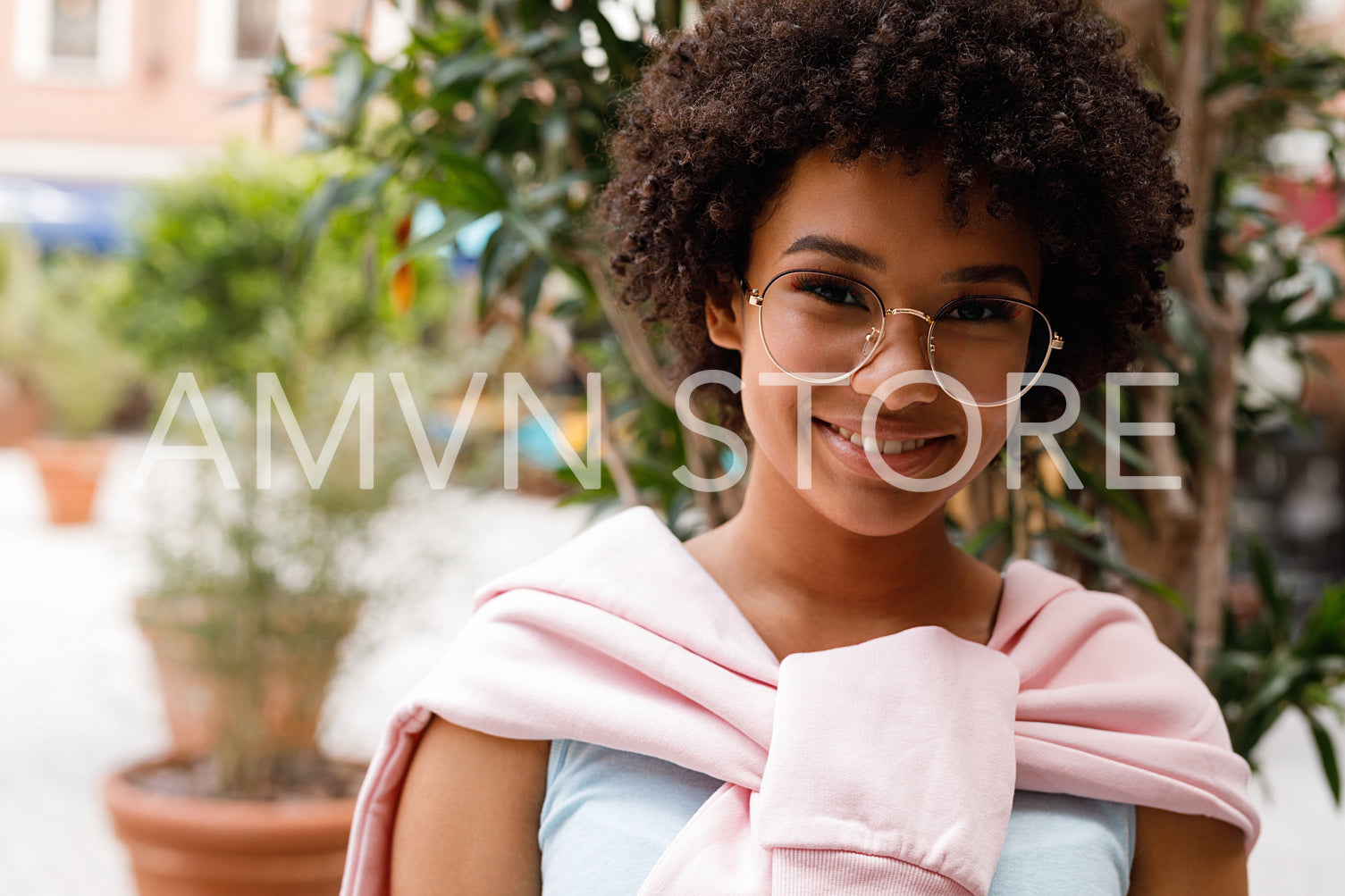 Outdoor portrait of a beautiful girl wearing glasses, looking at a camera and smiling	