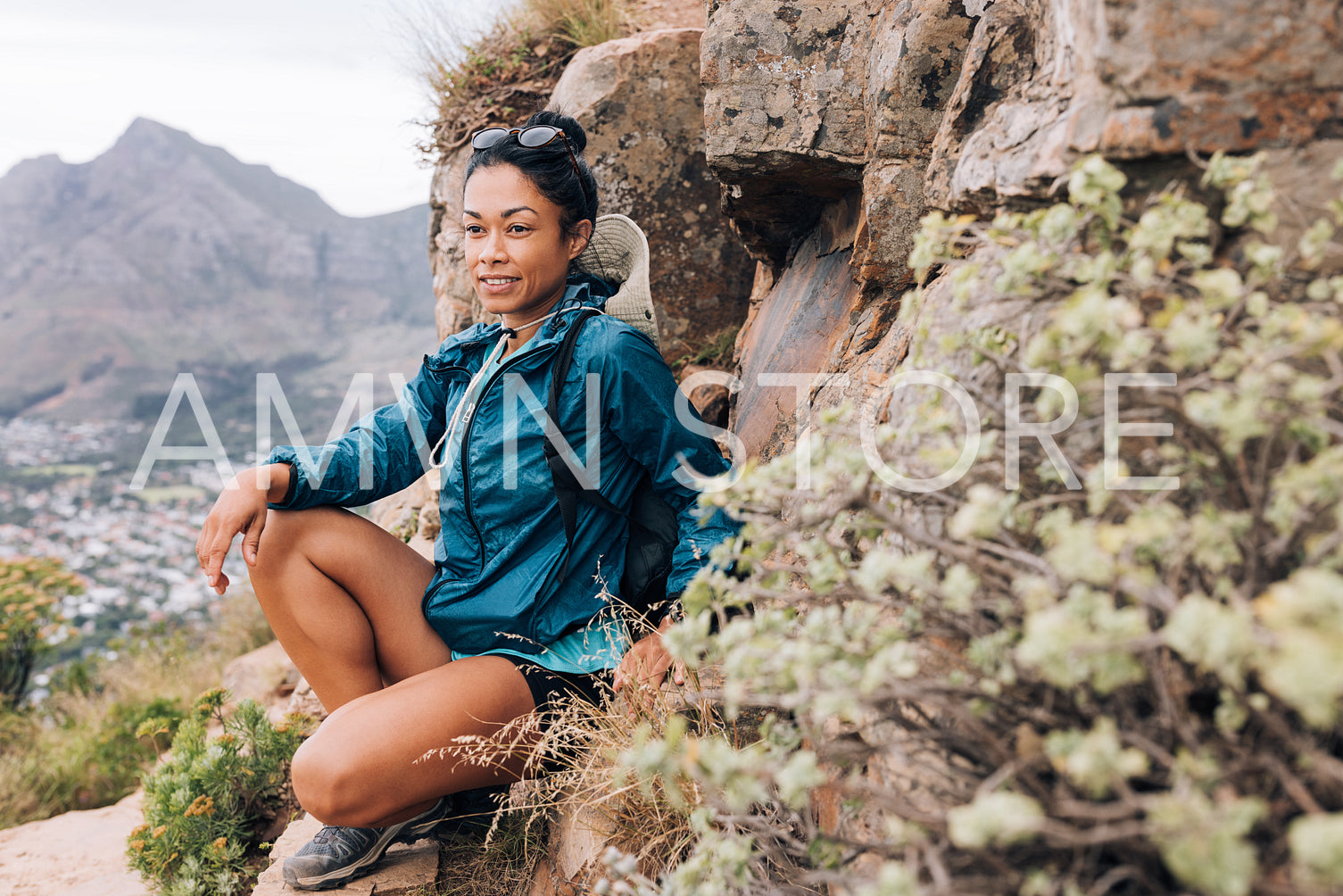 Young woman in sports clothes relaxing during mountain hike looking way, leaning rock