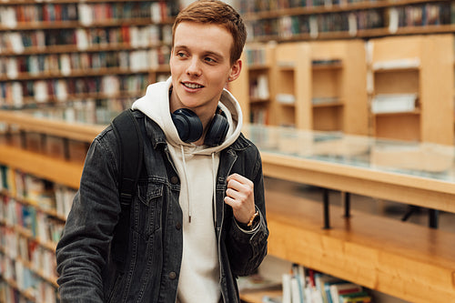 Portrait of a student in casuals standing in library and looking away