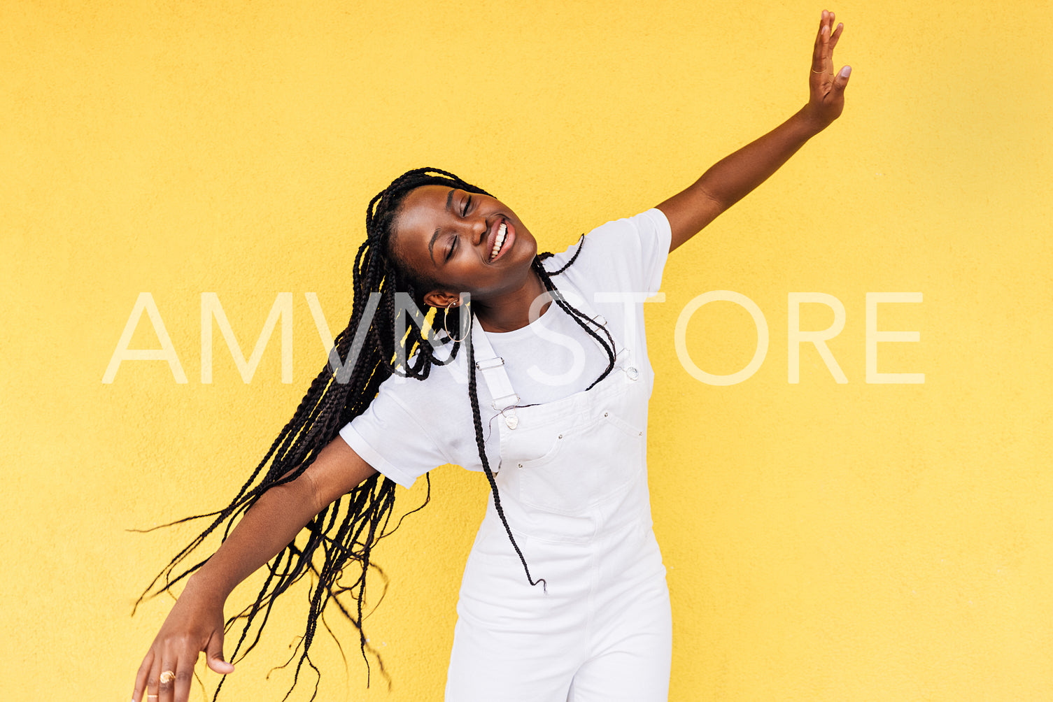 Smiling woman in white casual clothes having fun against a yellow wall outdoors