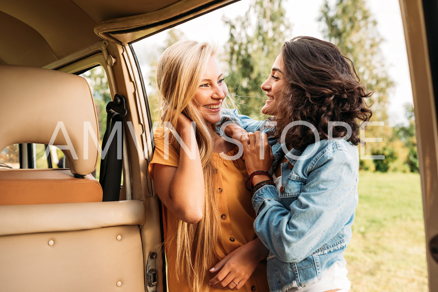 Two young women friends standing at camper van looking at each other