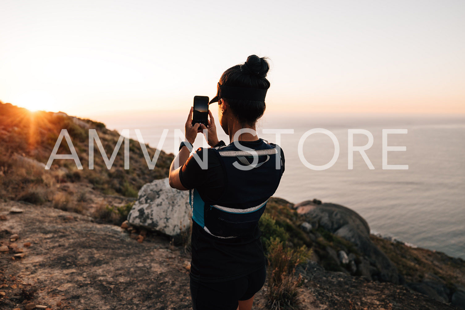 Rear view female hiker making photos of sunset on her smartphone