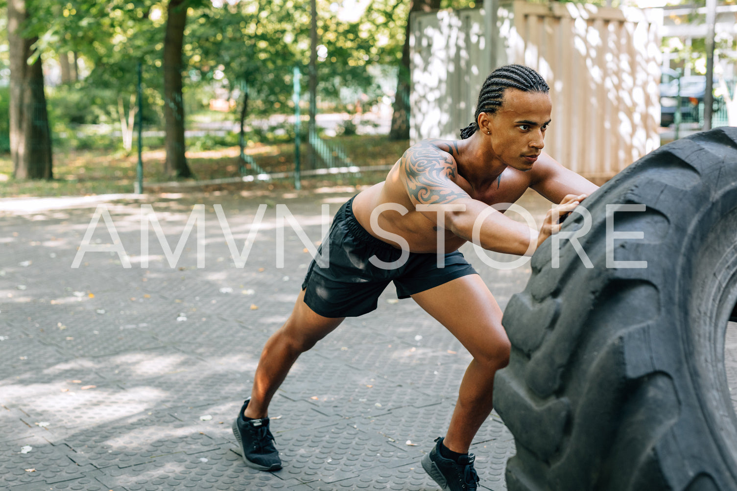 Young muscular man pushing large tire on sports ground	