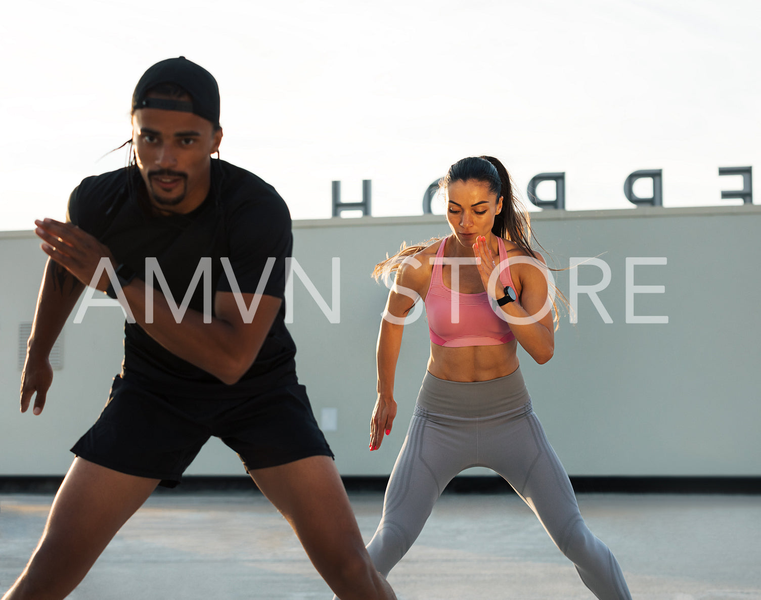 Man and woman are warming up before training on a rooftop. Fitness couple doing cardio exercises.