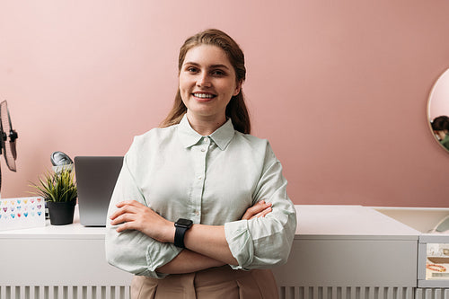 Portrait of a young boutique owner standing at counter. Smiling female in her clothing store.