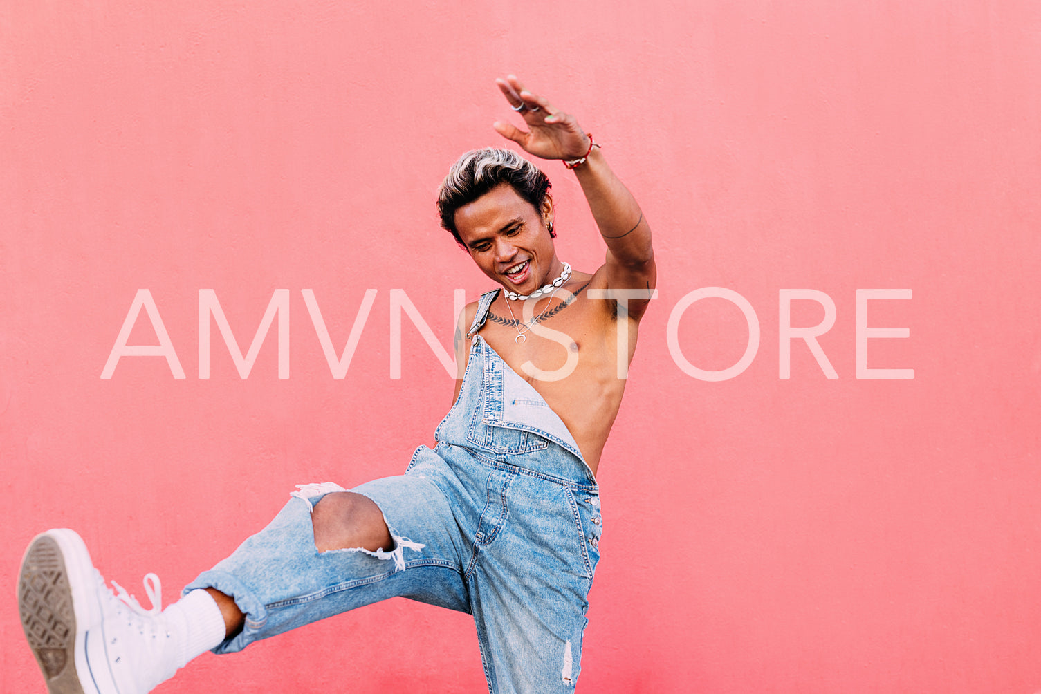 Smiling guy in denim overalls having fun outdoors against pink wall