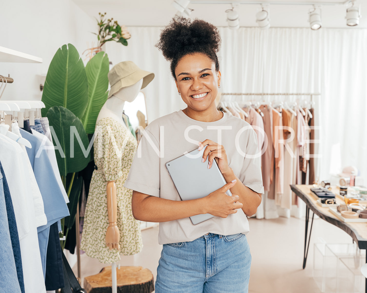 Portrait of a happy woman manager in small fashion store holding a digital tablet and looking at camera