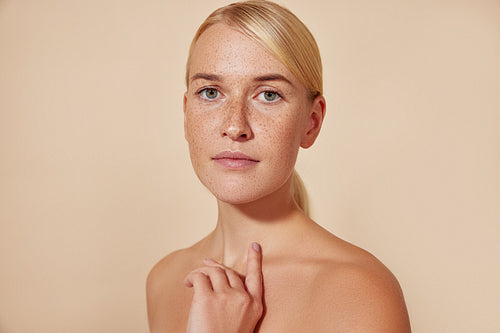 Portrait of a young blond female with freckles against pastel backdrop. Natural beauty woman with smooth skin.