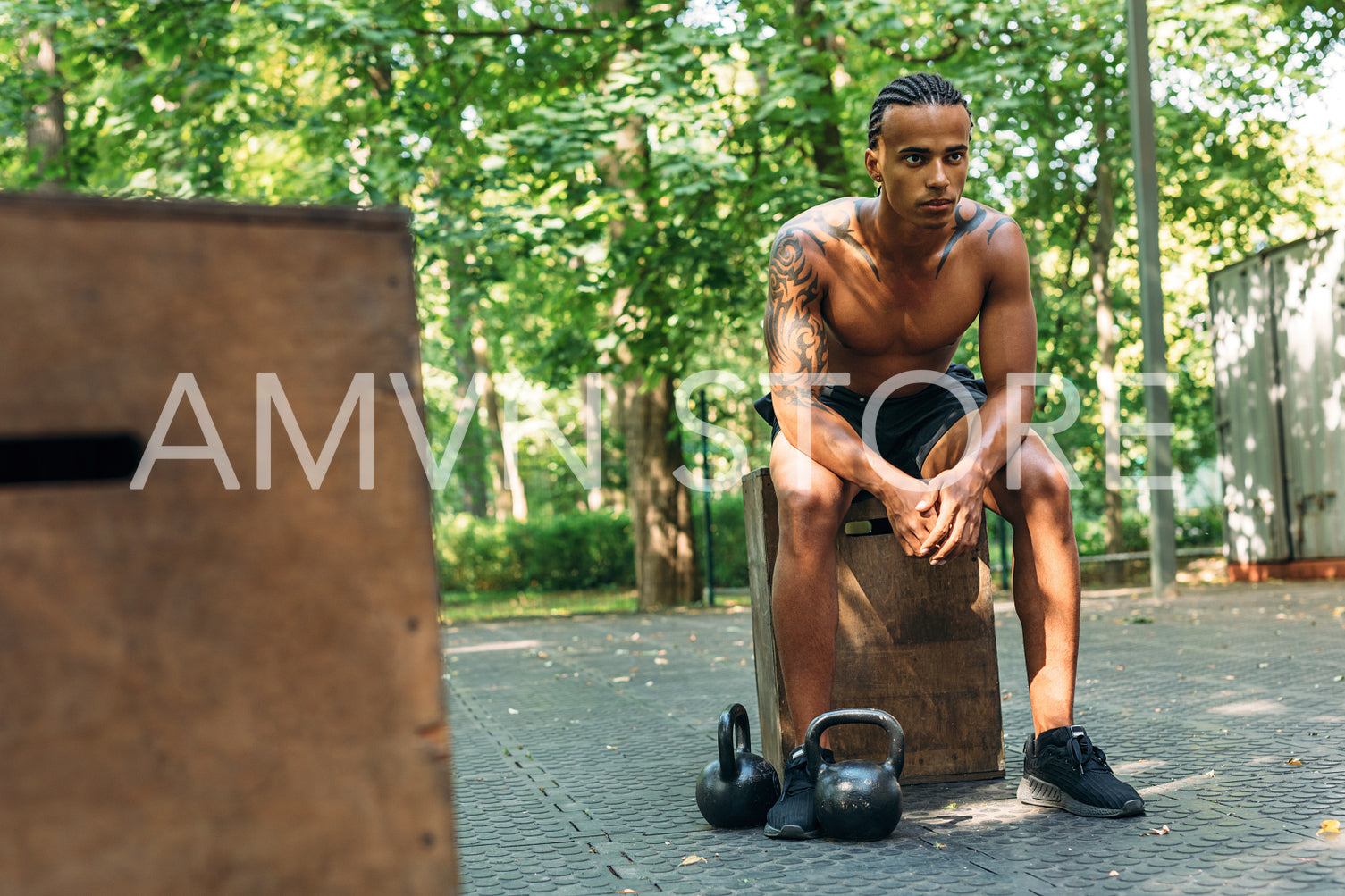 Young athlete resting during workout with kettlebells on the sports ground	