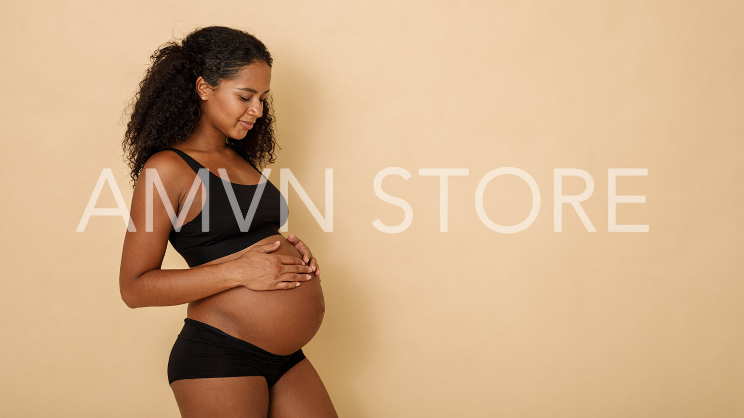 Studio shot of a pregnant woman looking on her belly, copy space