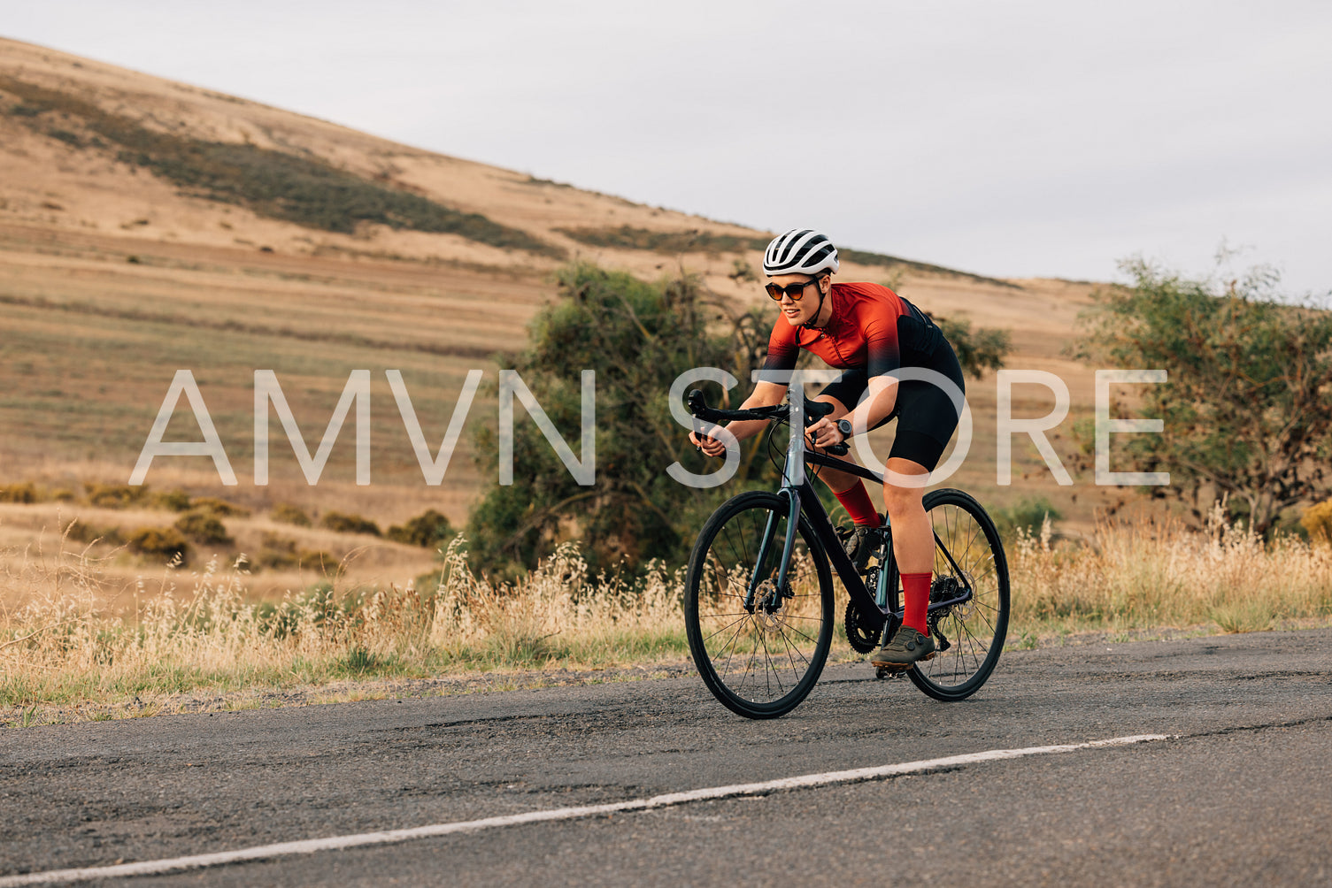 Athletic woman taking a bicycle ride on the empty countryside road. Professional cyclist practicing outdoors.