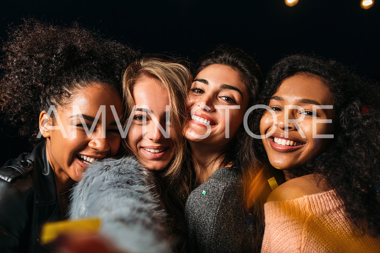 Group portrait of four happy female friends standing head to head at night outdoors