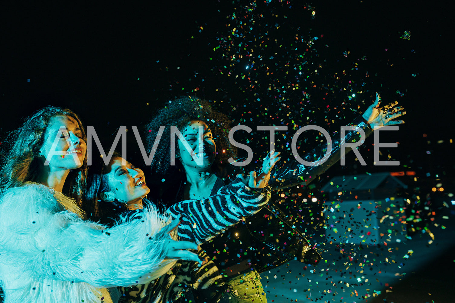 Three happy girls throwing confetti while standing on the roof under neon lights	