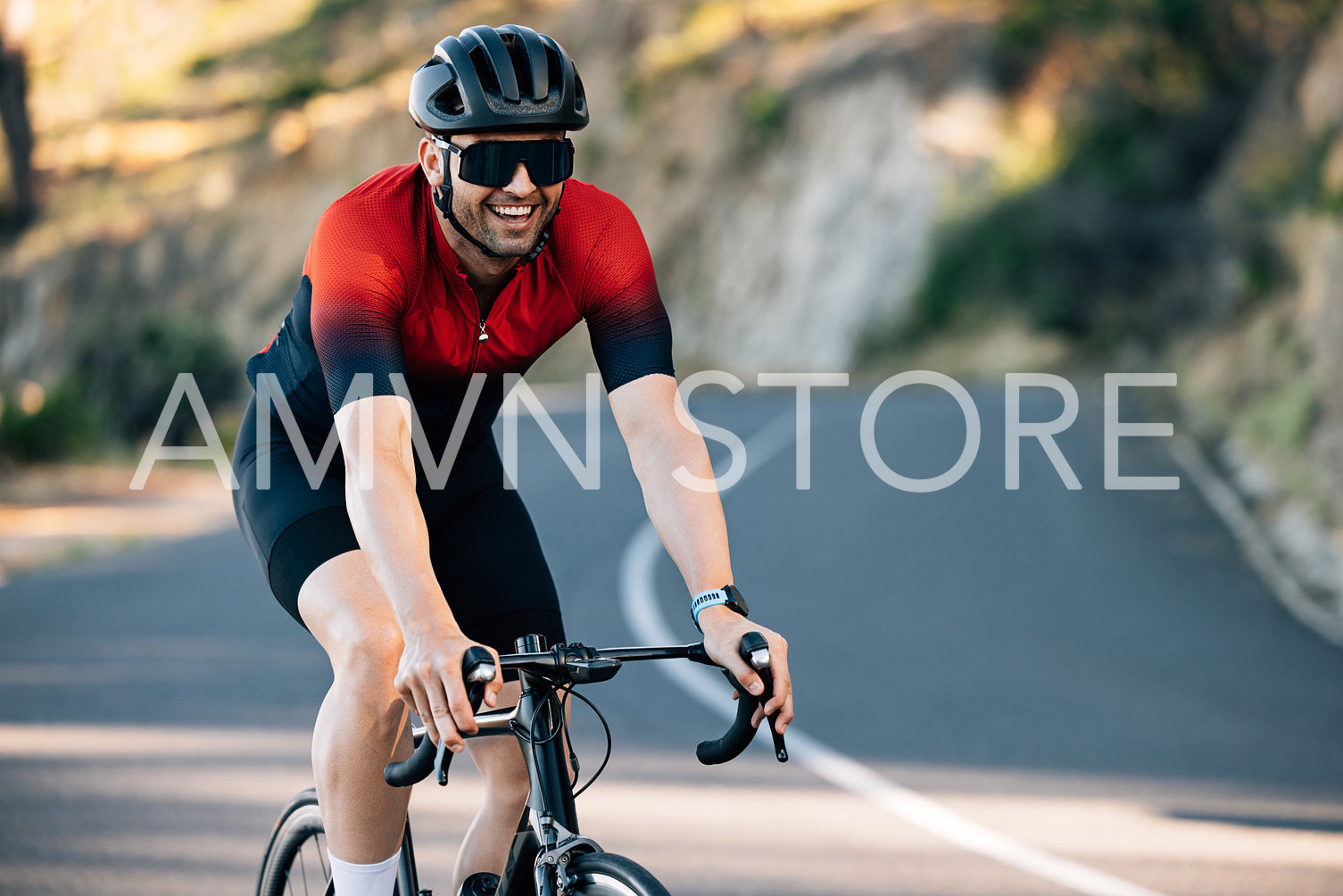 Young male cyclist smiling while riding a road bike on a hill