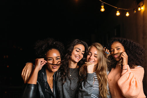 Night shot of young women making mustaches with hair