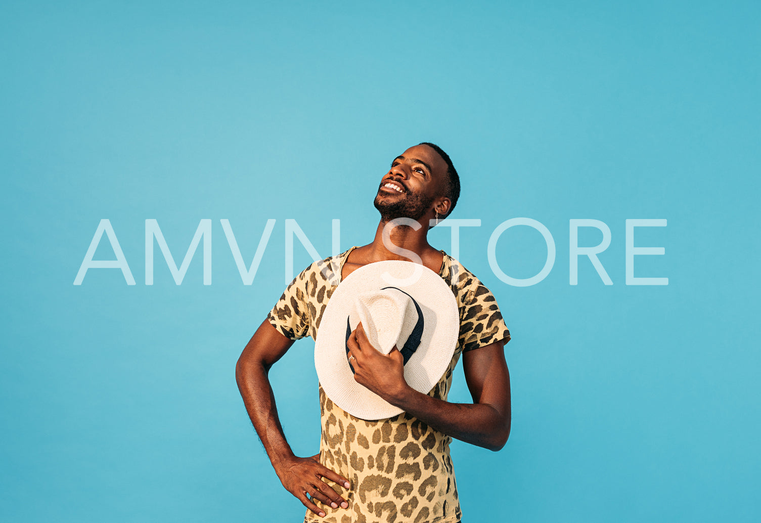 Young handsome man holding straw hat on chest and looking up