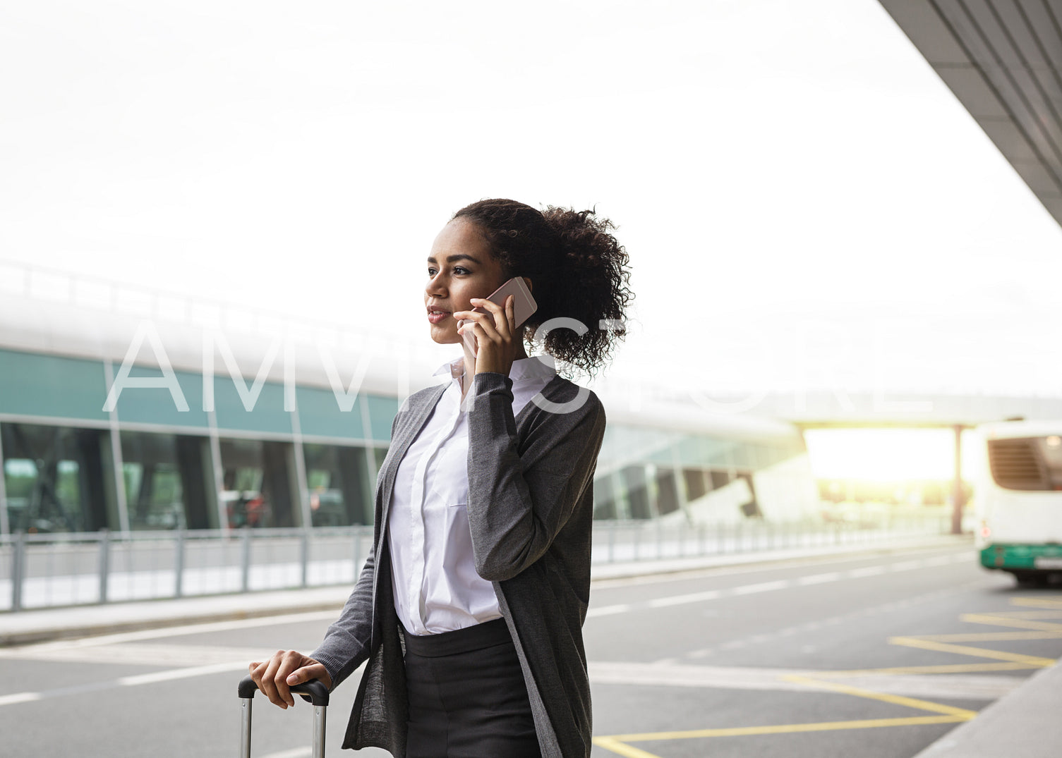 Young woman talking on mobile phone at airport terminal, waiting for a taxi	