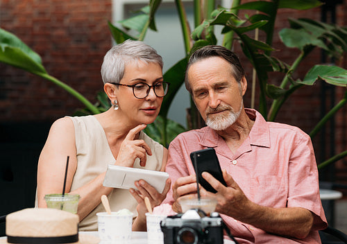 Mature couple using their smartphones while sitting outdoors