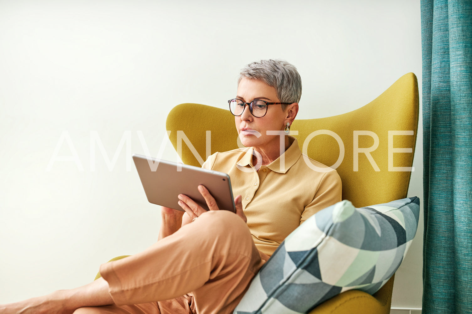 Stylish senior woman holding a digital tablet while sitting in living room	