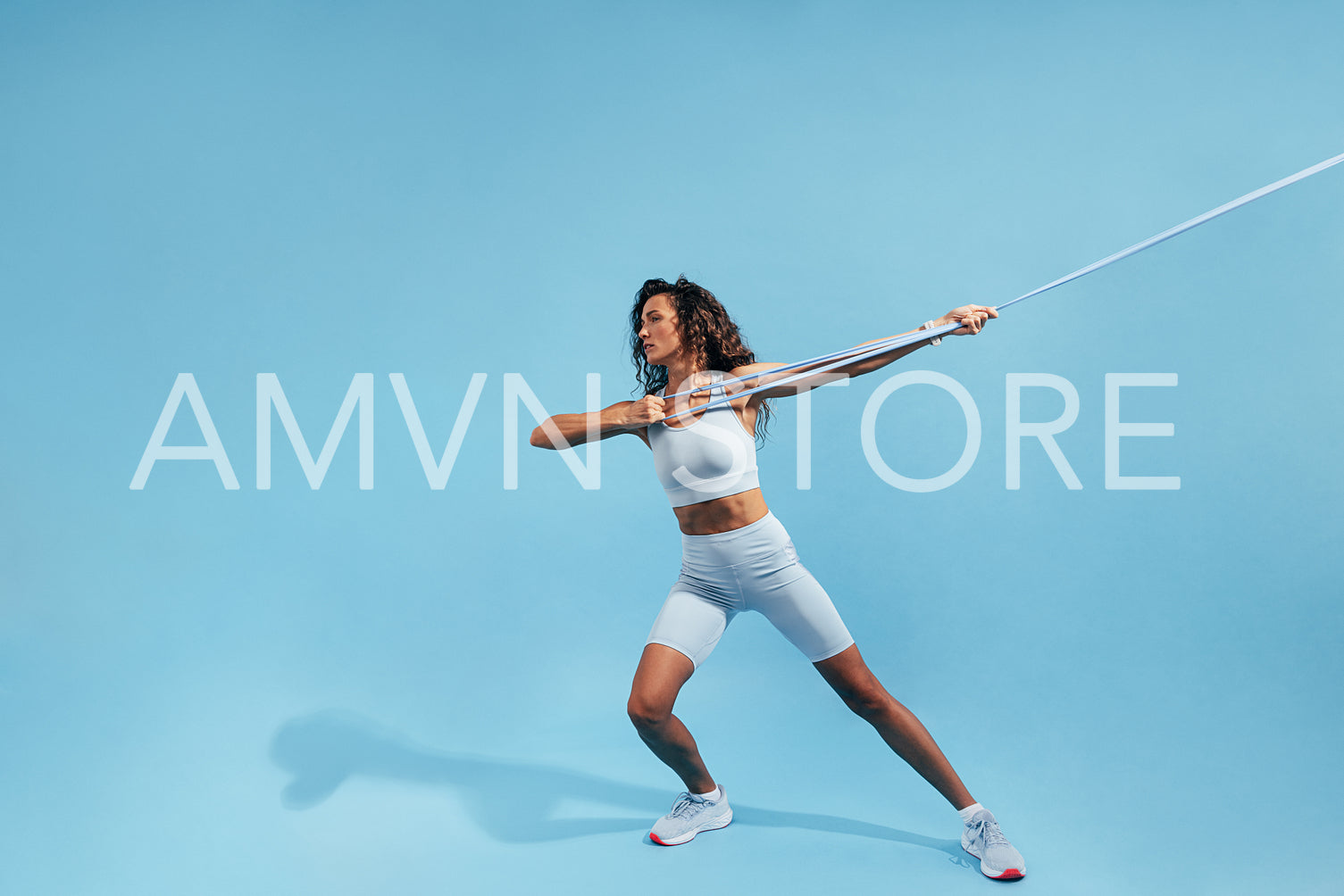 Muscular woman pulling resistance band. Young female in sportswear doing intense exercises with elastic band.