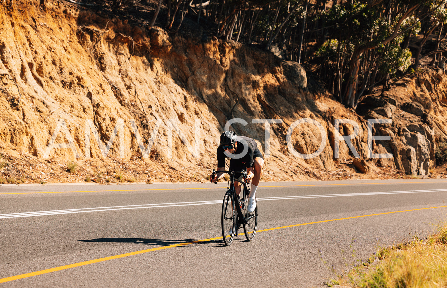 Professional sportsman riding his bicycle on an empty road in wild terrain. Male cyclist practicing riding on bicycle.