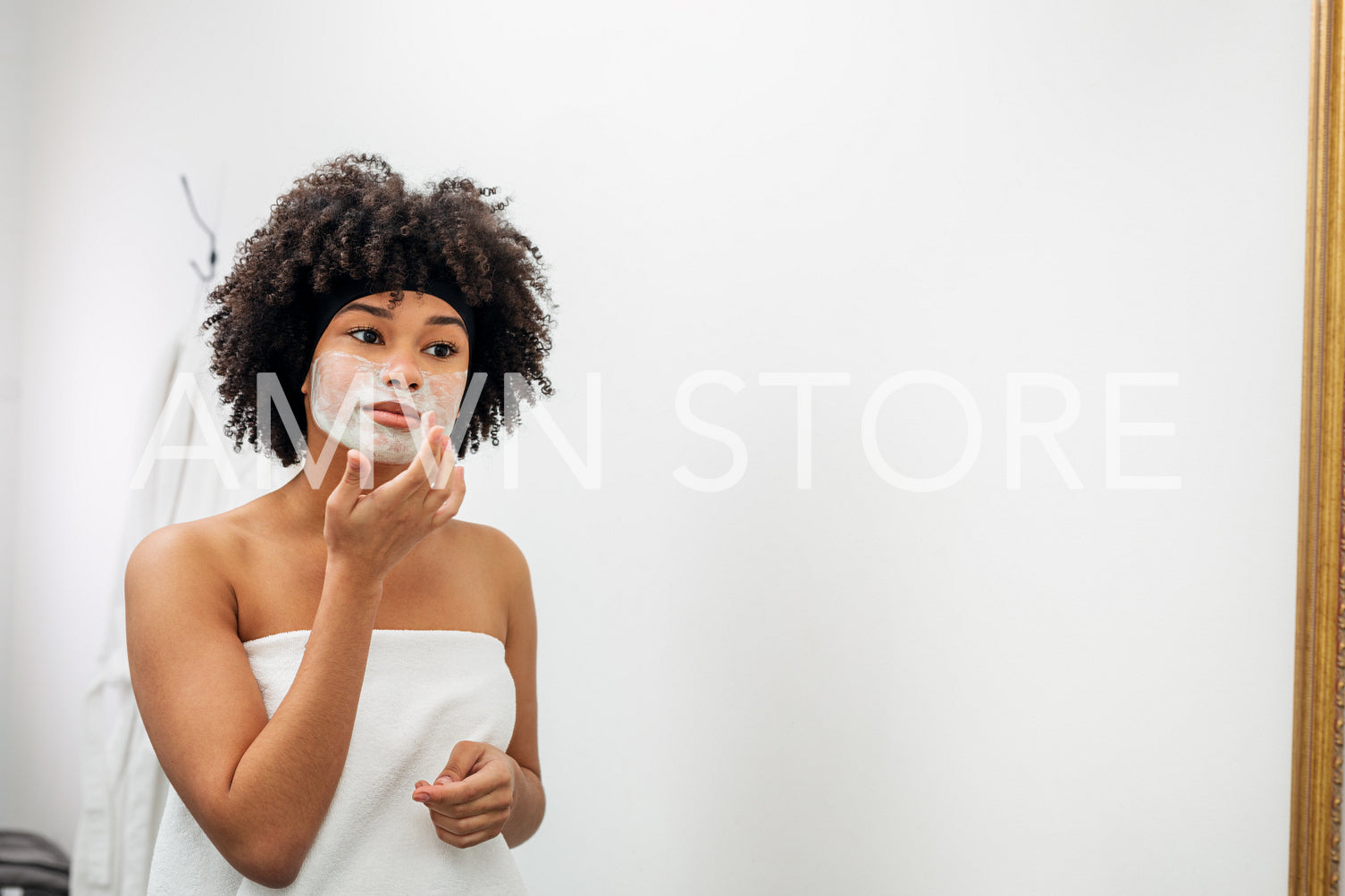 Woman applying facial mask in front of bathroom mirror	