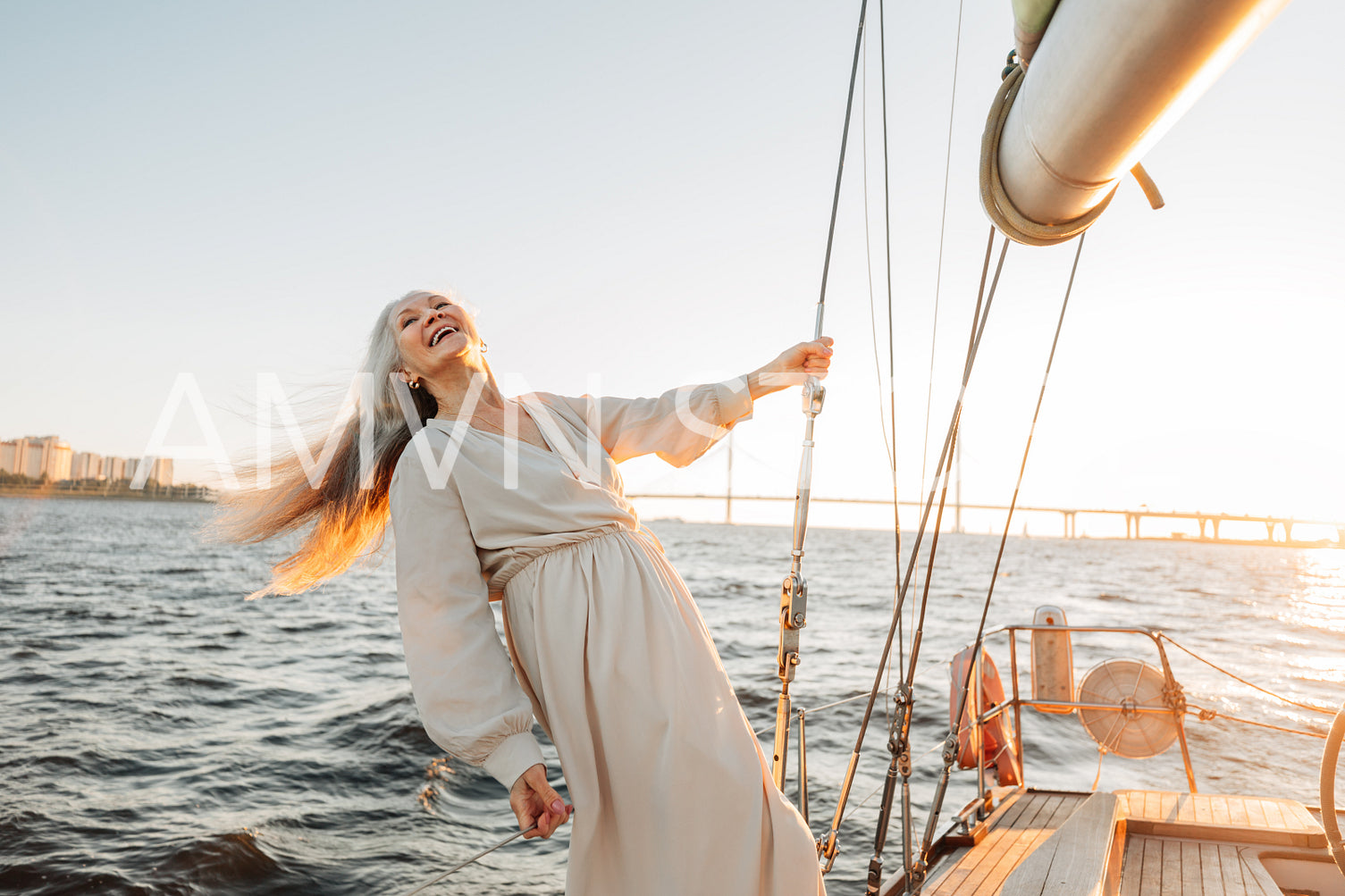 Happy senior woman wearing dress holding a rope on yacht	