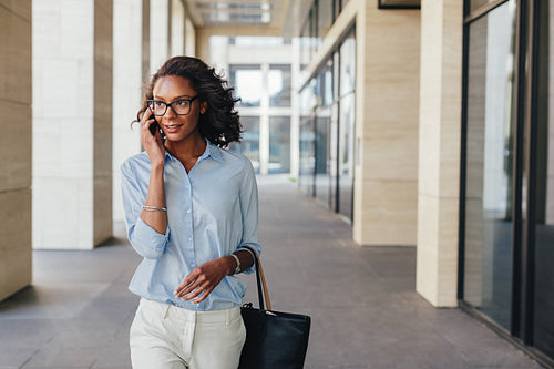 Woman in formalwear walking outdoors and using mobile phone