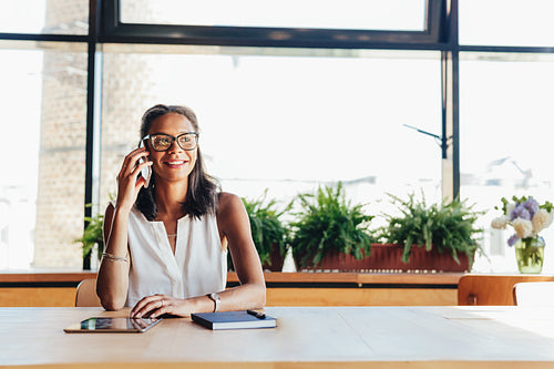 Happy businesswoman talking on smartphone. Female entrepreneur in cafe.