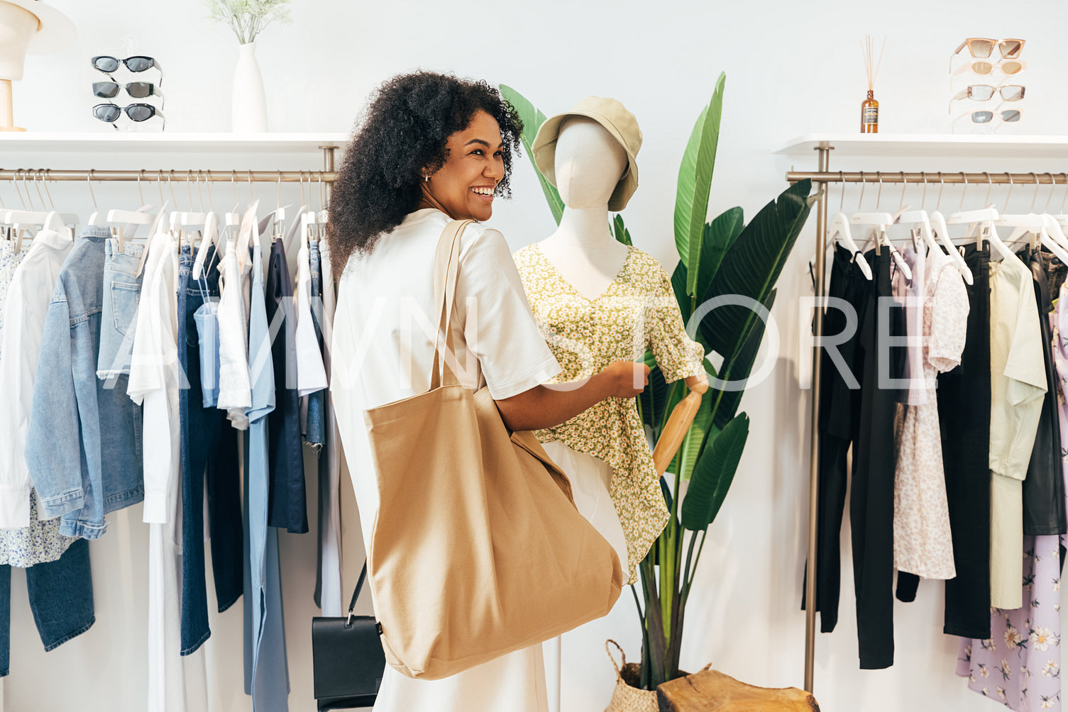 Cheerful woman standing in a boutique at mannequin looking away