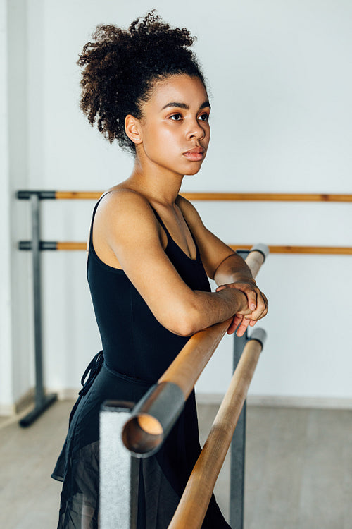 Portrait of African American ballet dancer standing at barre in studio