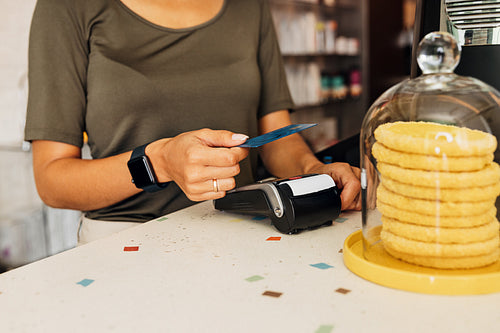 Midsection of unrecognizable female using credit card in cafe