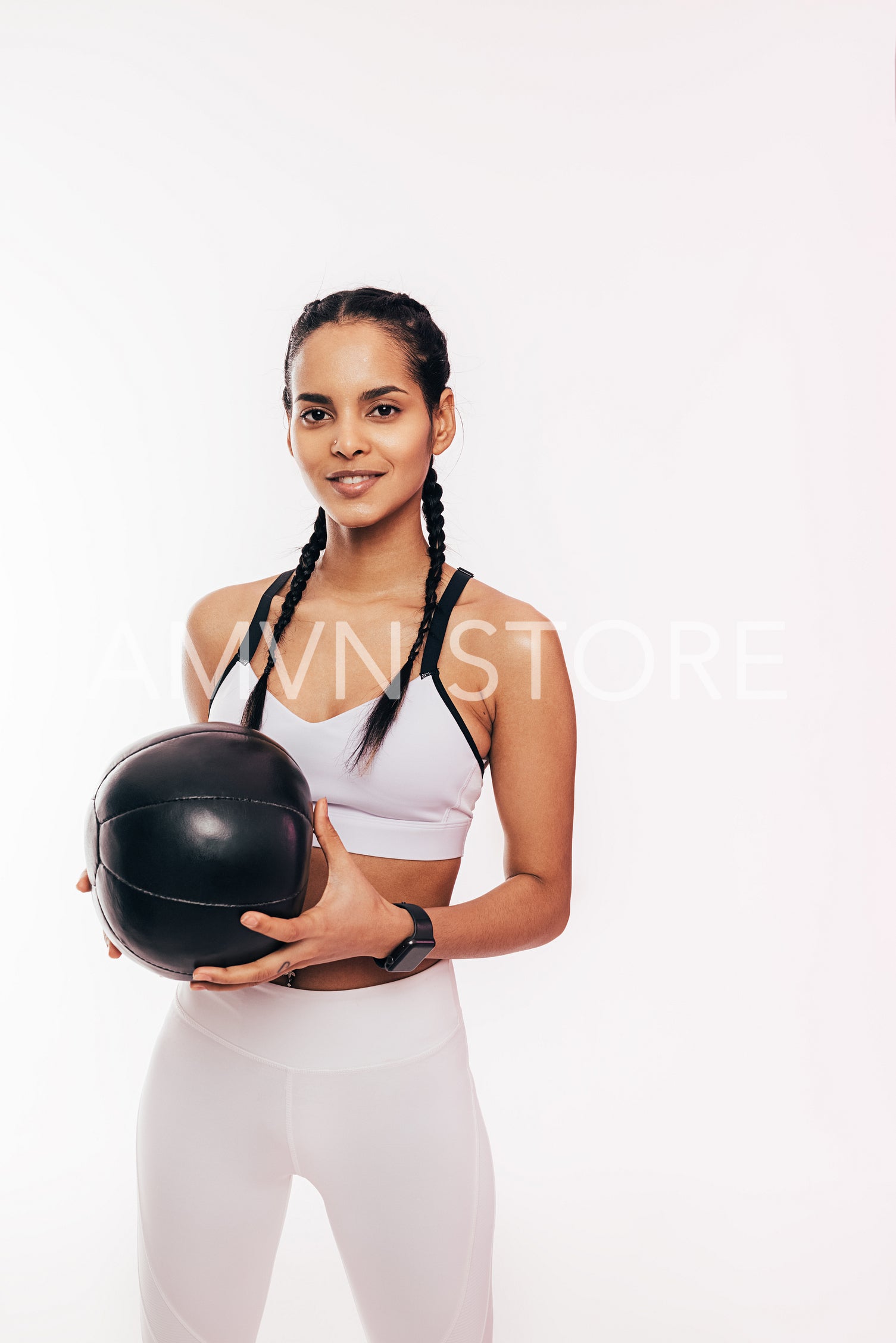 Smiling mixed race woman holding a medicine ball in the studio	