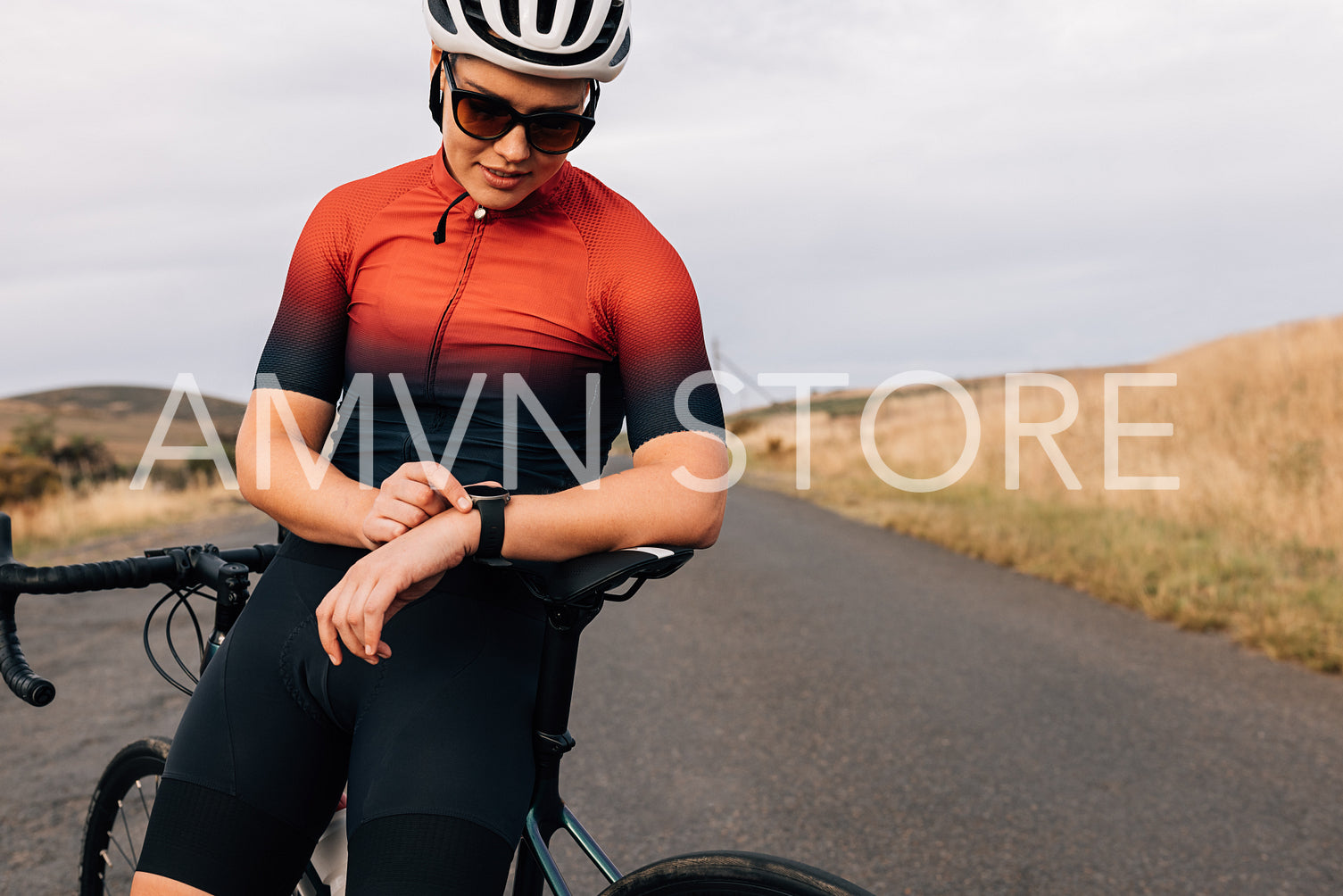 Woman cyclist leaning on bike checking pulse on digital watch while standing on a road