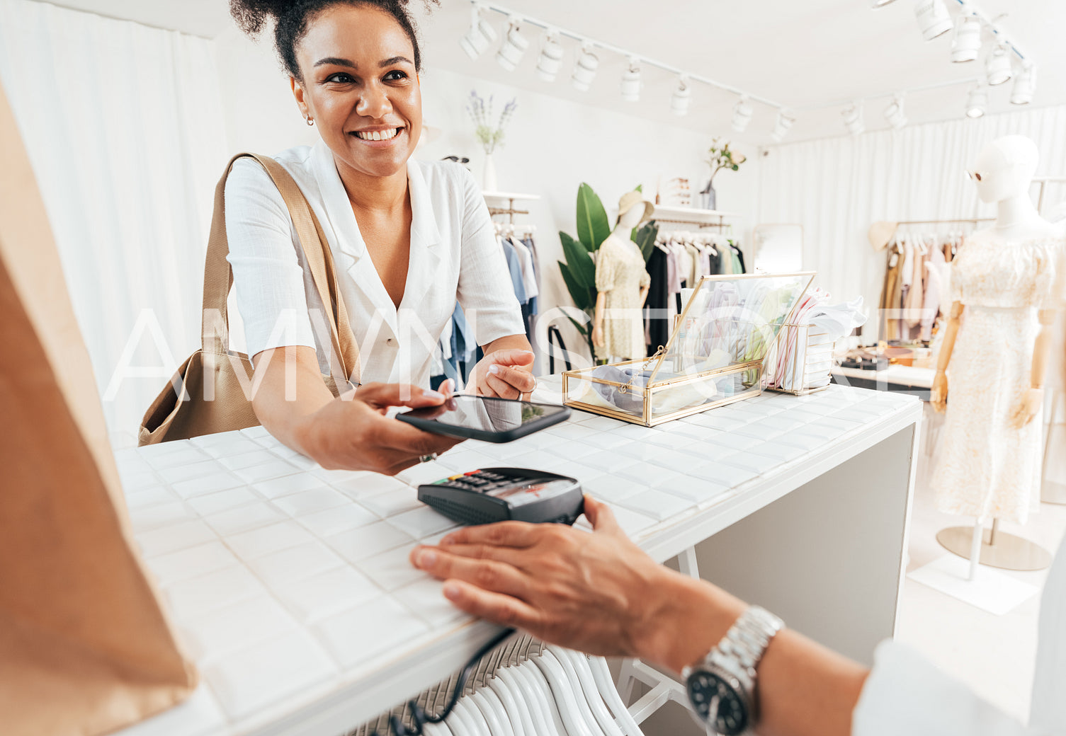 Happy customer paying through smartphone at a counter in a clothing store