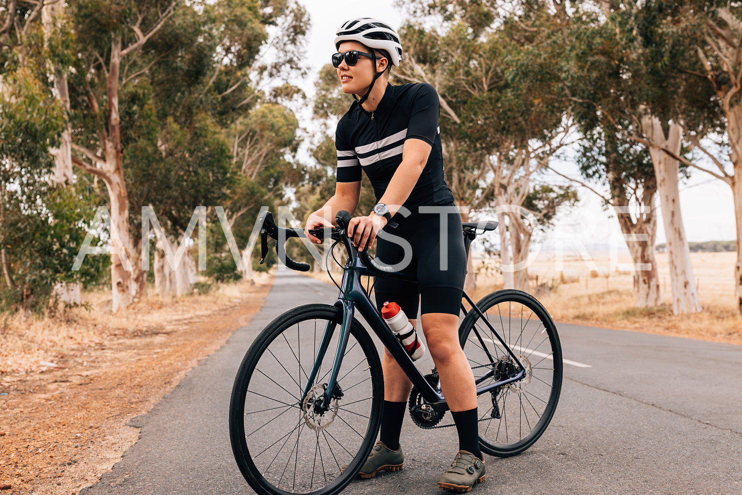 Professional cyclist in sportswear holding on board computer on bike looking away 