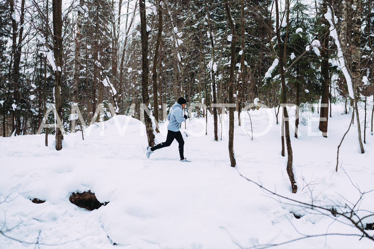 Side view of young sportsman exercising in snow forest	
