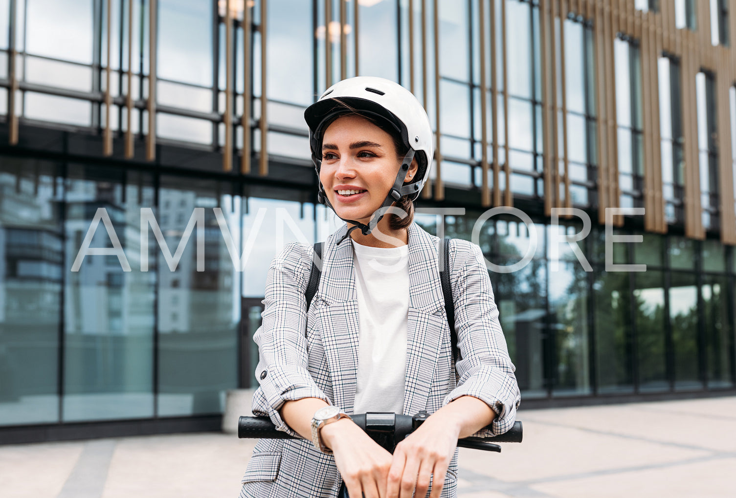 Beautiful smiling woman wearing cycling helmet looking away while standing in the city