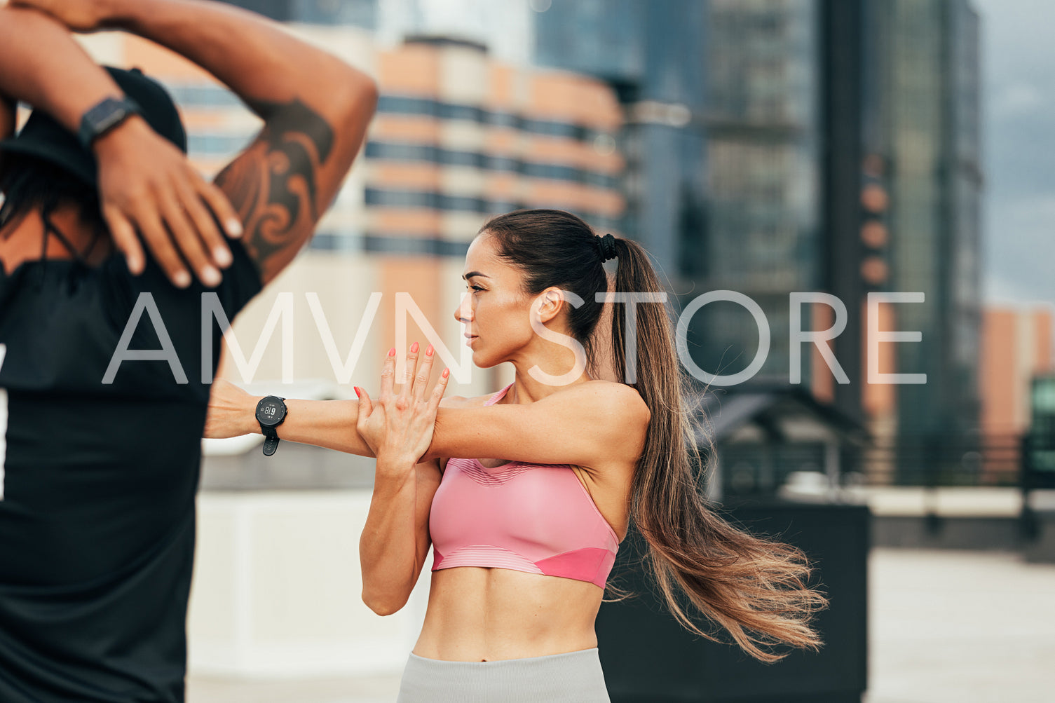 Young slim woman stretching her arm on a rooftop