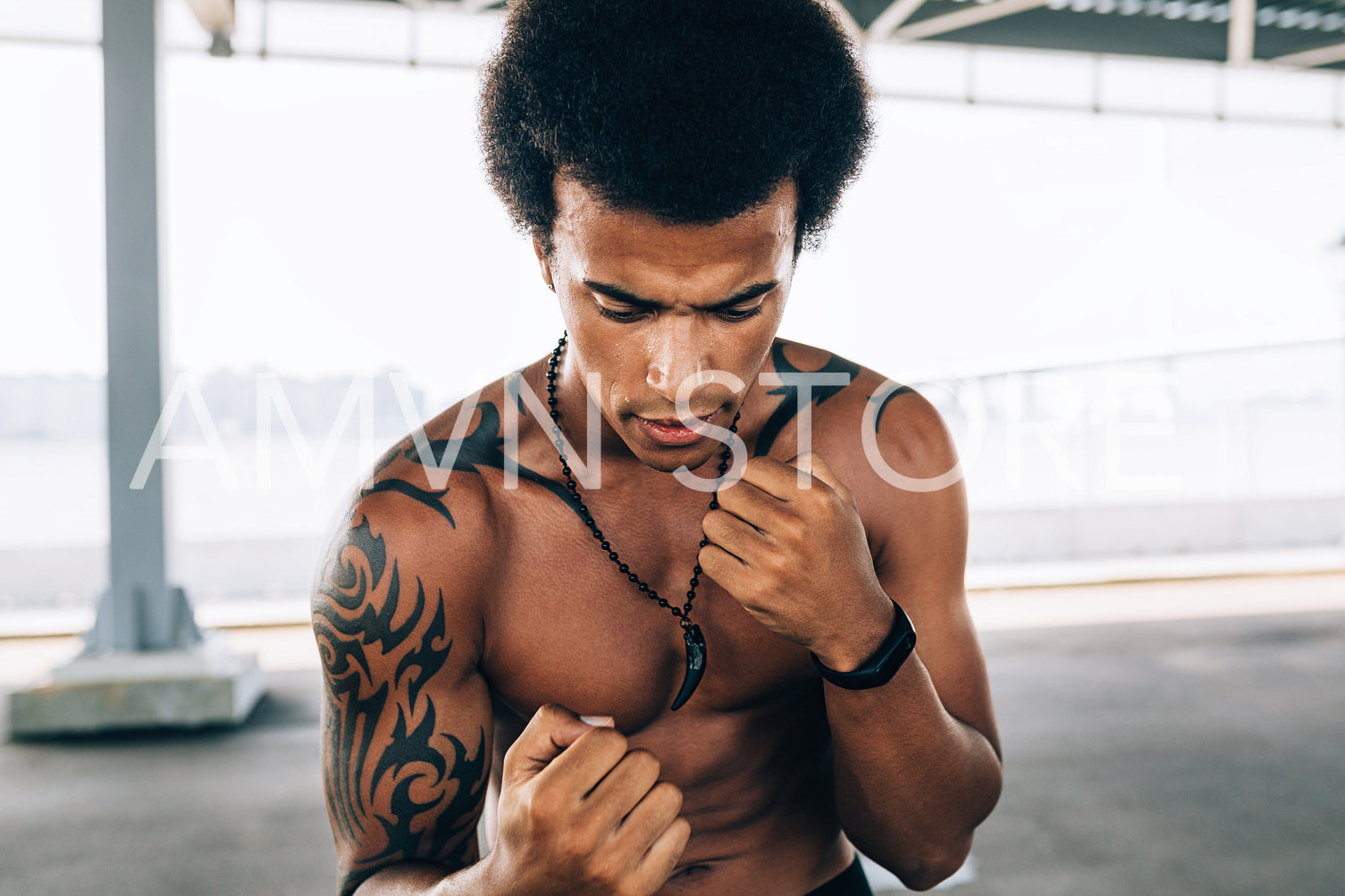 Confident shirtless sportsman fighter standing with fists up and looking down	