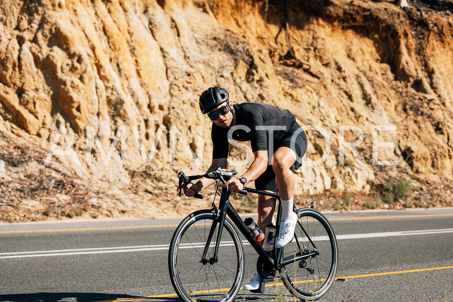 Male rider in helmet and glasses looking at camera while riding his bicycle