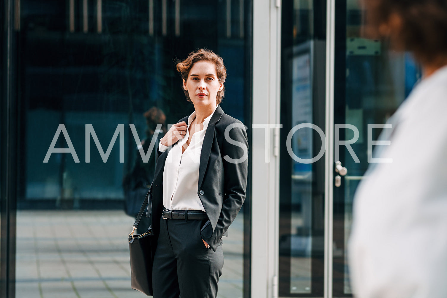 Young entrepreneur standing in front of an office building and looking away	