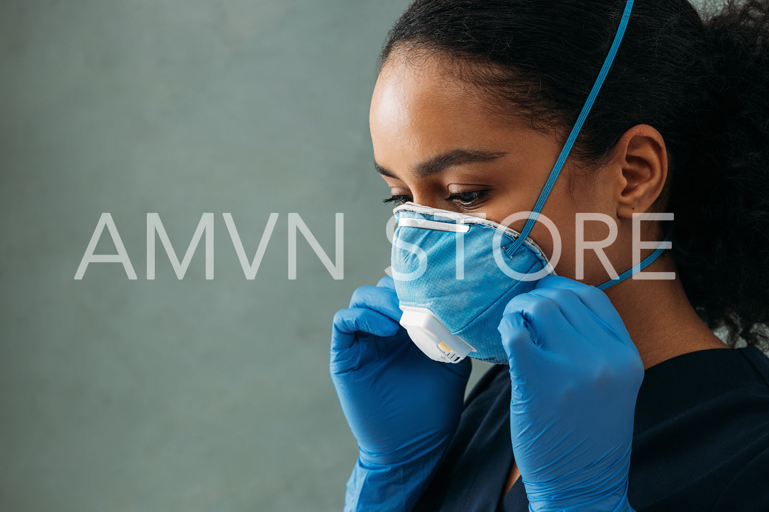 Close up of young nurse adjusting respirator on her face	