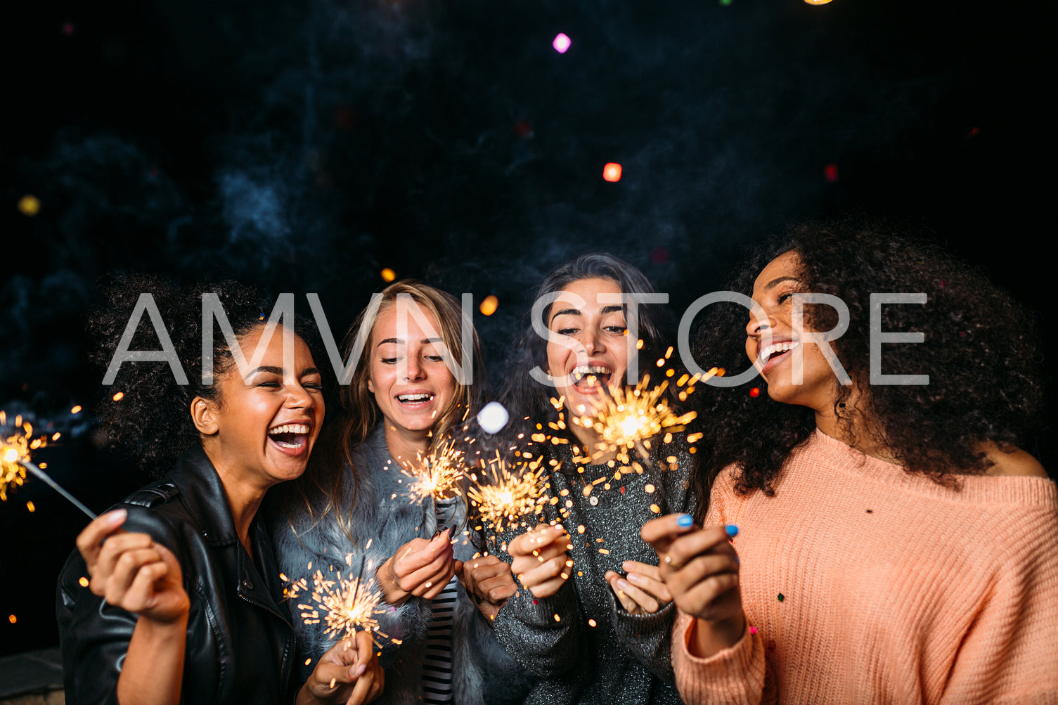 Outdoor shot of laughing friends with sparklers, standing together at night