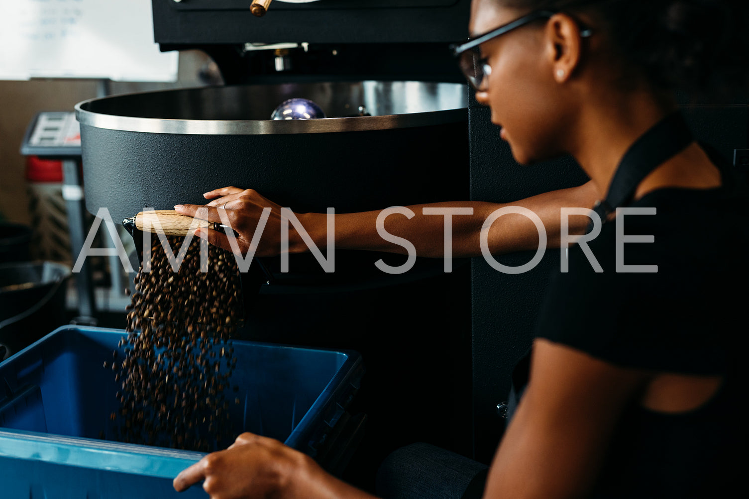 Female barista using industrial coffee roasting machine in cafe	