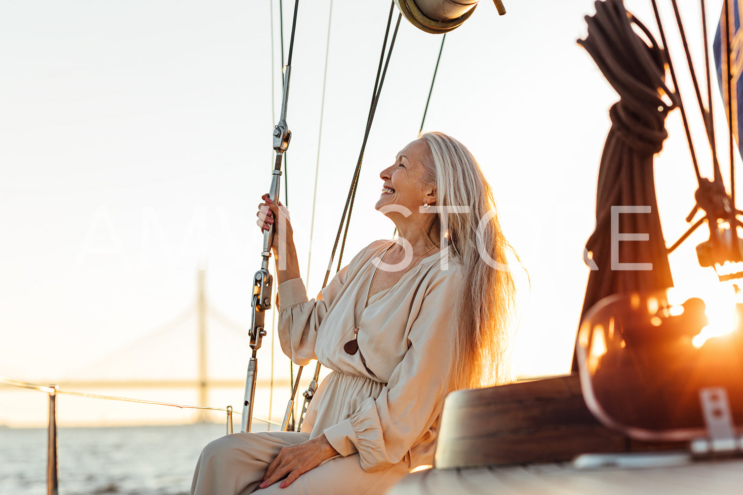 Side view of mature woman with long hair sitting on yacht and smiling	