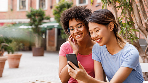 Two female friends live streaming from outdoor cafe